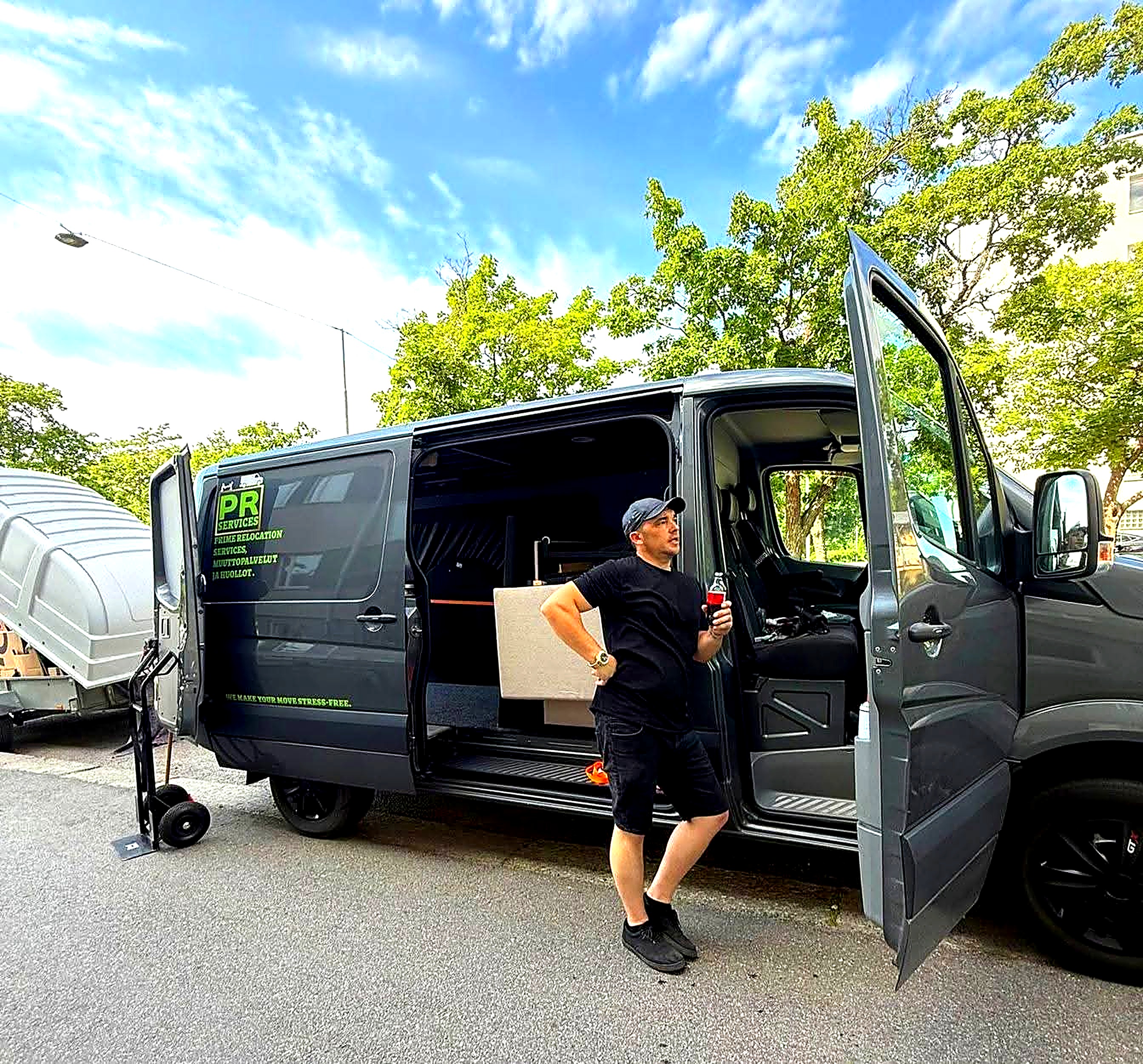 Black Prime Relocation van with neon green brand accents at a Finnish waterfront